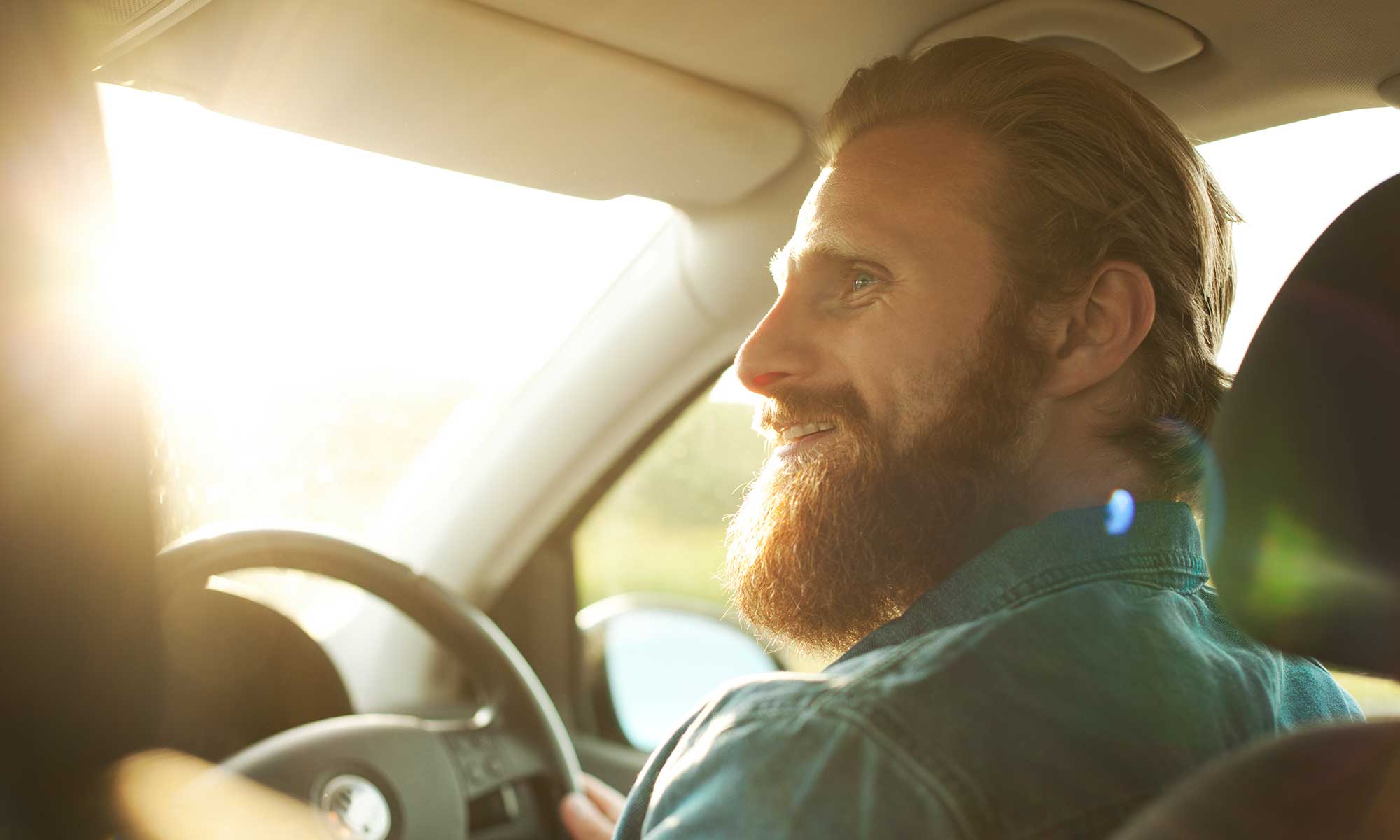 Man driving a car and smiling to his passenger