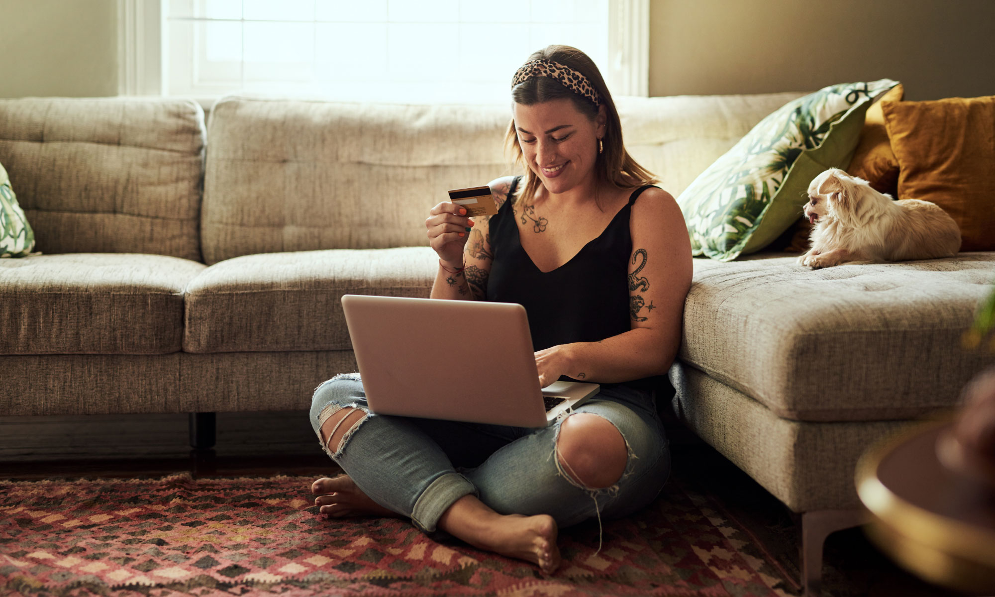 Young adult woman with her dog looking at deals on her laptop