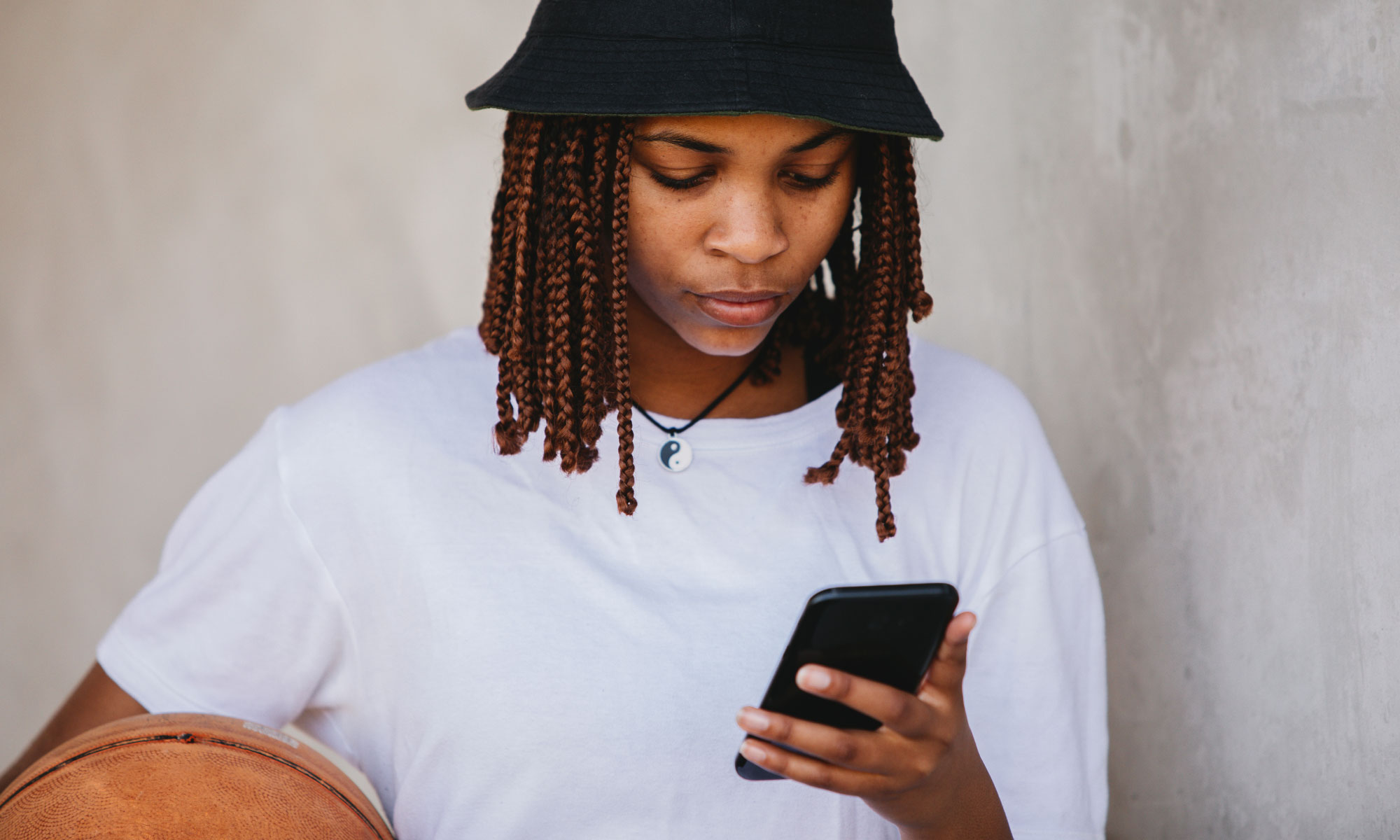 Young adult woman looking at her phone wearing a bucket hat