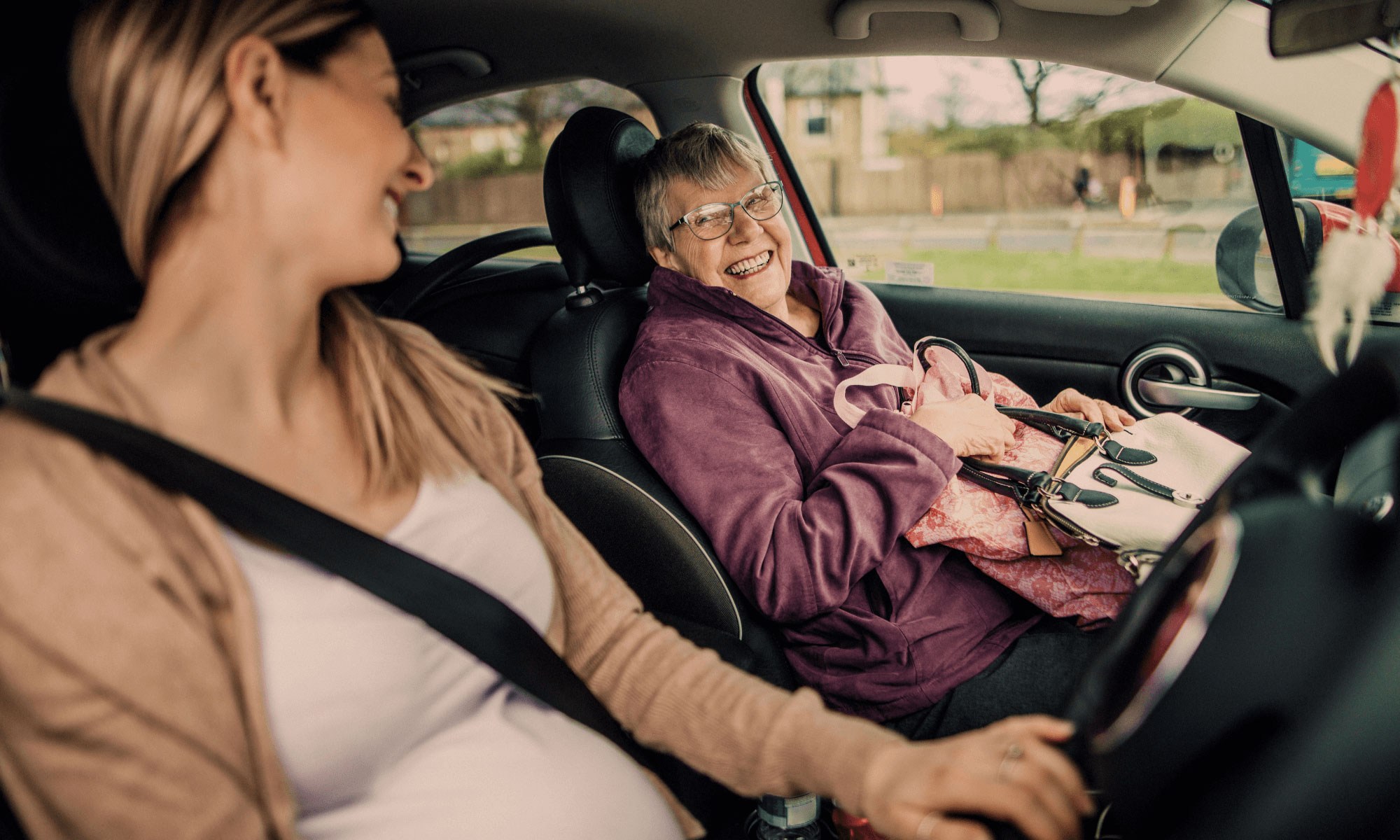 Pregnant and senior woman driving a car