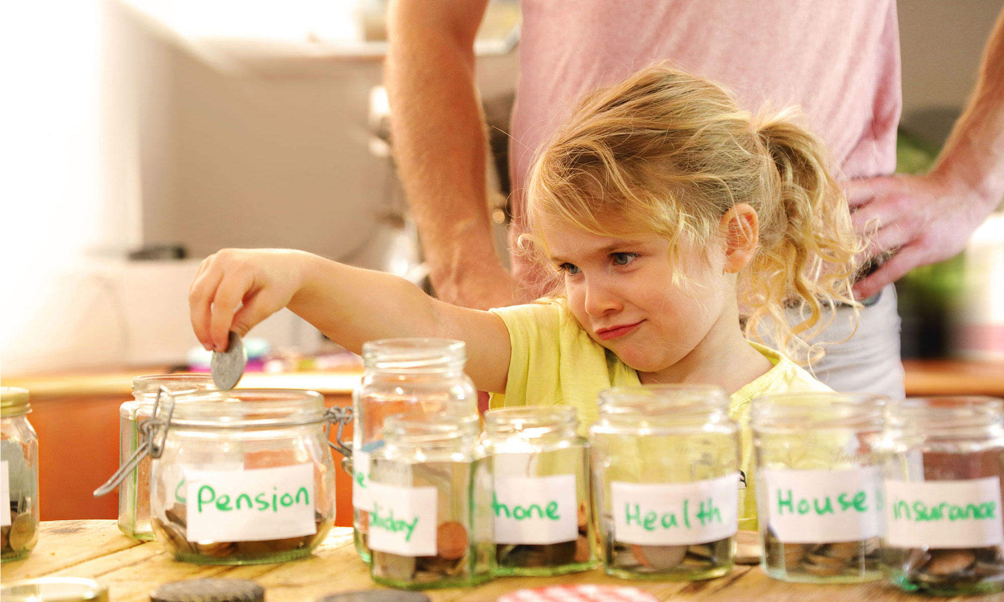 Little girl portioning out her pocket money in labelled jars