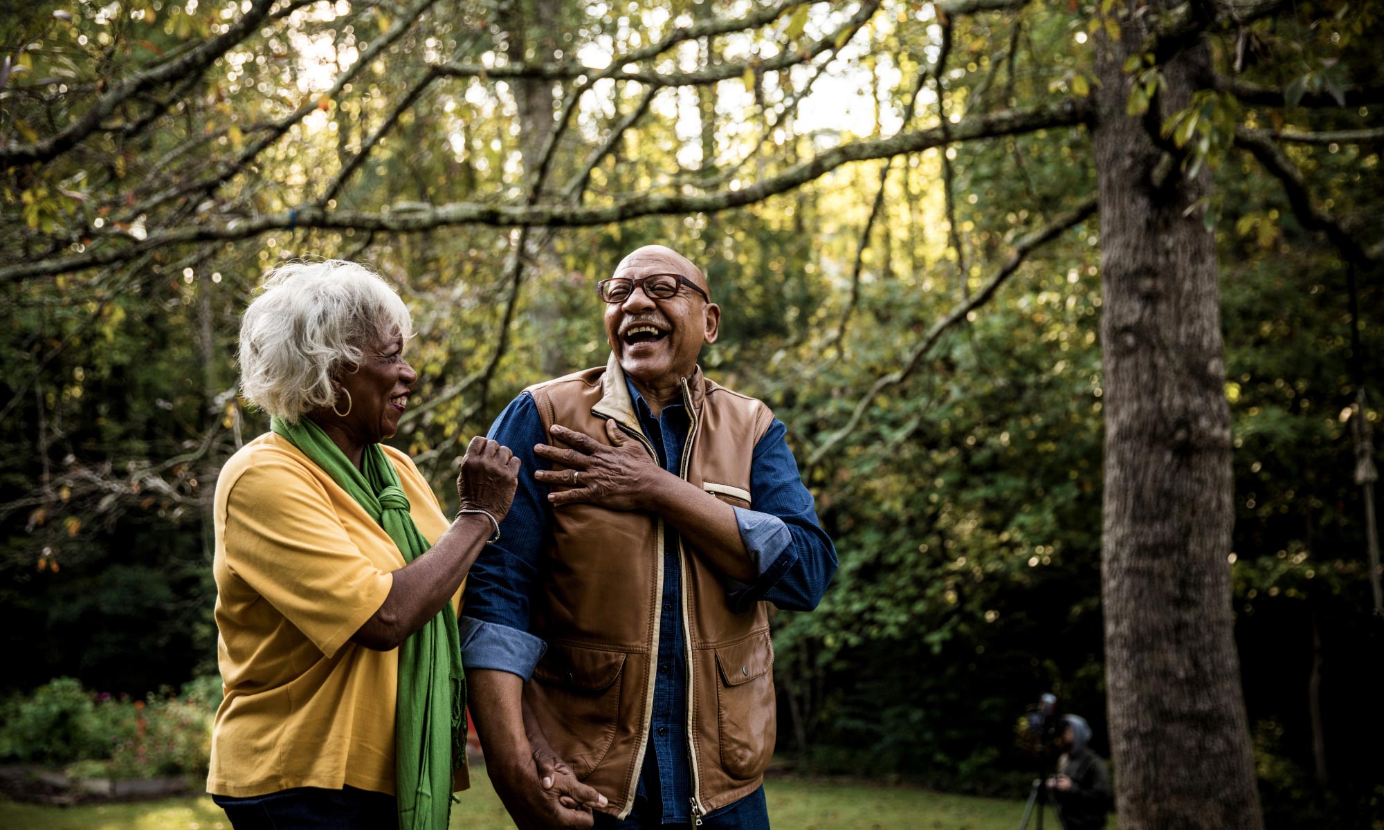 A mature couple laughing while walking in the forest