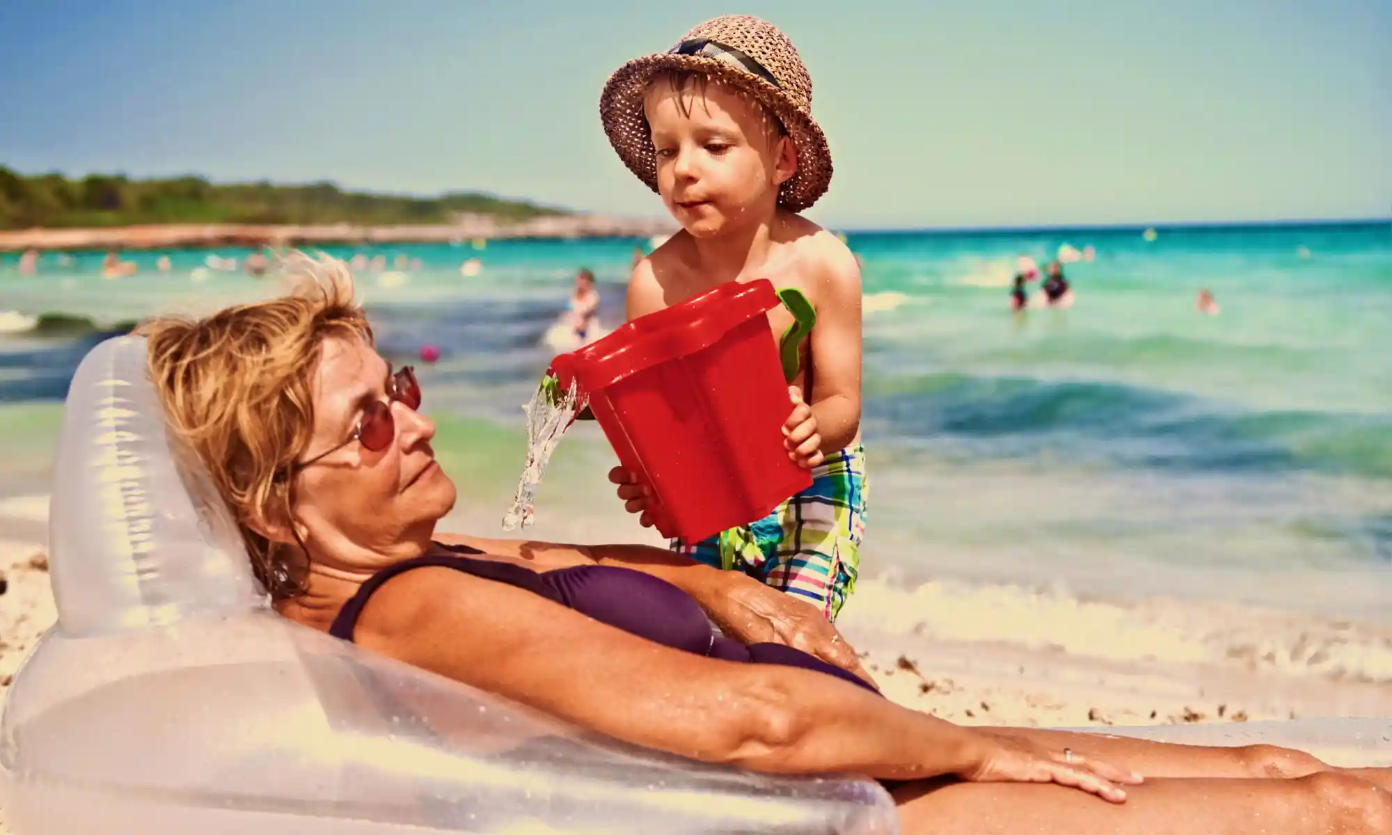 Senior woman lying down on the beach with her grandson