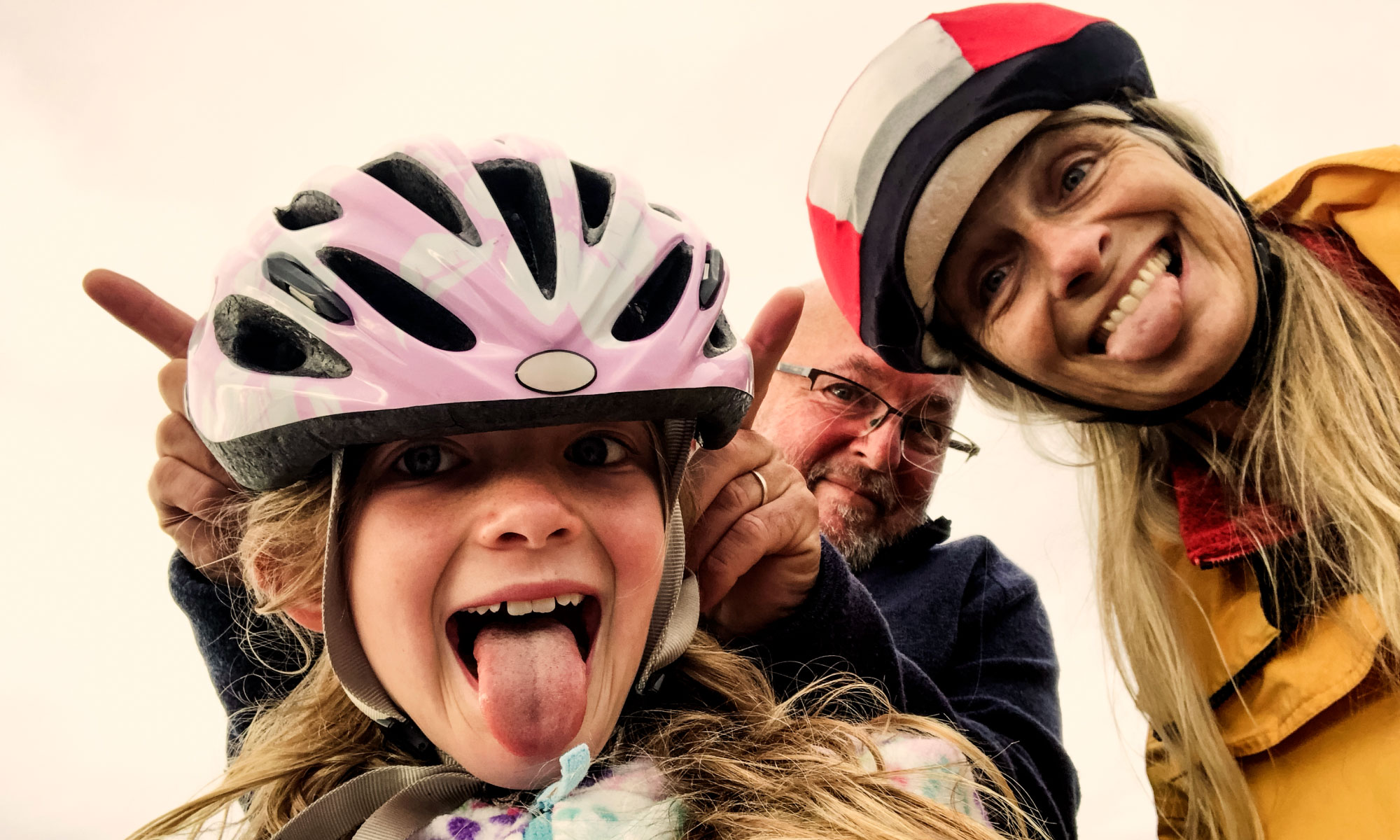 a family wearing bicycle helmets and poking their tongues out